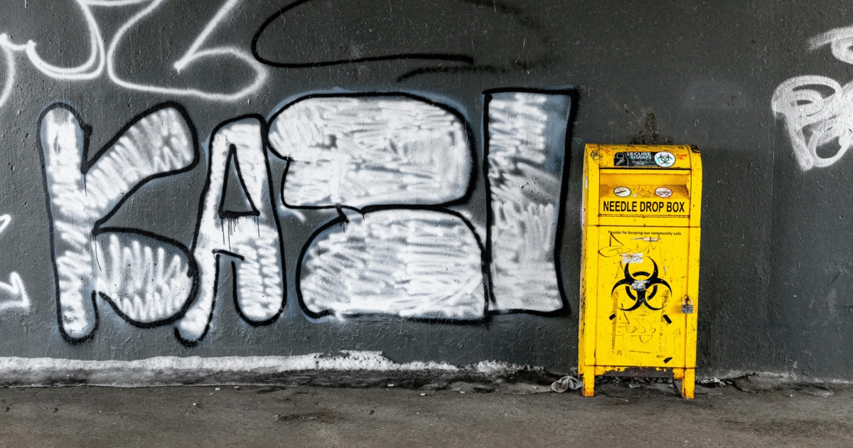 Yellow and Black Garbage Bin Beside Wall With Graffiti